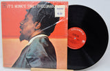 Vinyl record with cover featuring a man's profile against an orange background, on a light gray surface.