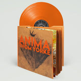 An orange vinyl record partially pulled from its illustrated album sleeve, shown on a clean light gray background. The sleeve reads 'ANIMA THOM YORKE' in orange text over a brown abstract design.
