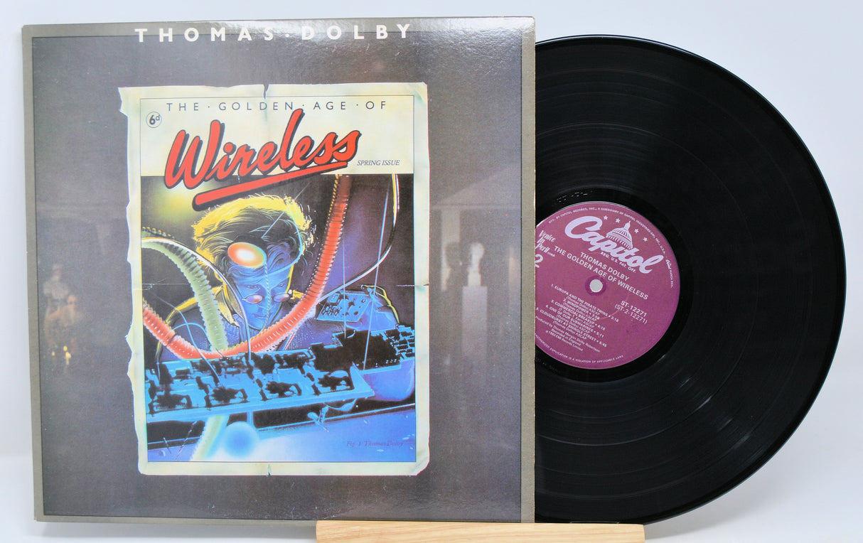 Thomas Dolby album 'Wireless' with vinyl record and cover, featuring a neon-lit cityscape and the title 'Wireless' prominently displayed.