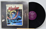 Thomas Dolby's 'The Golden Age of Wireless' vinyl record album shown with its outer jacket and the black record partially pulled out. The album cover features a colorful sci-fi illustration, and the record label is Capitol Records.
