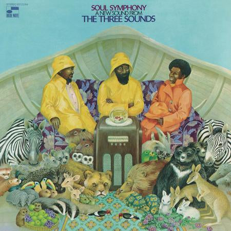 Album cover art for Soul Symphony's 'A New Sound From The Three Sounds', featuring three men in raincoats seated in a boat with zebras, lions, kangaroos, and other animals gathered around a jukebox against a light blue sky.