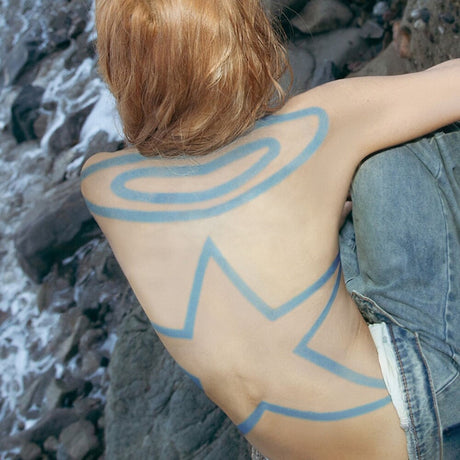 Person with blue abstract design on their back sitting on a rocky surface