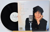 Vinyl record with cover featuring a person and microphone, on a white background