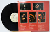 Vinyl record with a black and white album cover showing a band in a studio setting.