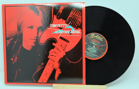 Vinyl record with cover featuring Tom Petty holding a guitar, on a red background.