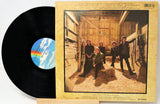 Vinyl record with a colorful label and cover featuring a group of people in a barn.