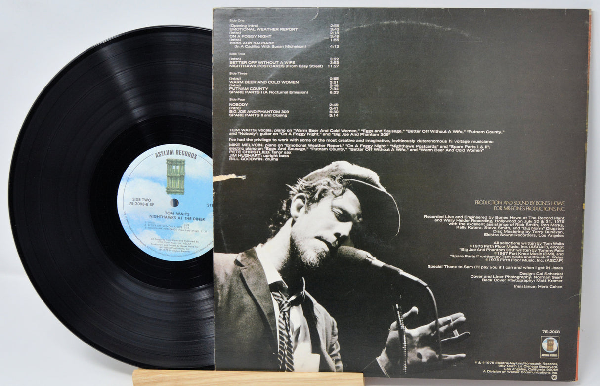 Vinyl record 'Tom Waits Nighthawks At the Diner' with back cover featuring a person holding an instrument on a light gray background