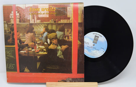 Vinyl record 'Tom Waits Nighthawks At the Diner' with cover featuring a scene from a movie, on a white background