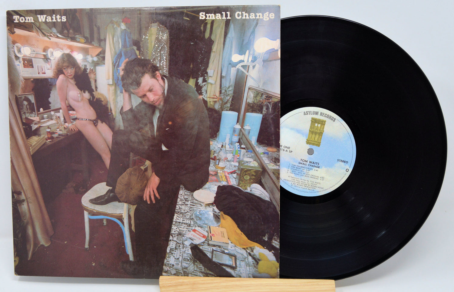 Vinyl record 'Tom Waits Small Change'  with cover featuring a stylized illustration of a man and woman in a room, and a visible label.