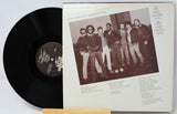Vinyl record with cover featuring a group of people on a white background