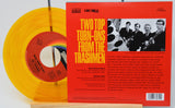 Vinyl record with a red label and yellow disc, featuring a cover with text and a band image.