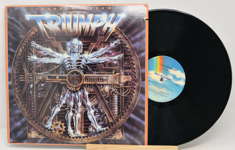 Triumph 'Thunderstagen' vinyl record LP with the illustrated album cover standing beside the black record on a small wooden stand.