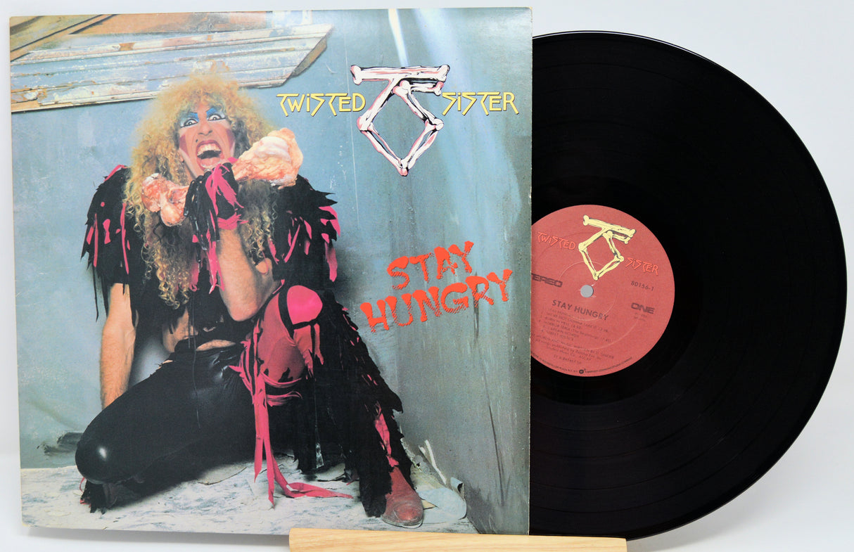 Twisted Sister 'Stay Hungry' vinyl record album with the printed cover in front and the black LP record partially pulled out, showing the orange center label.