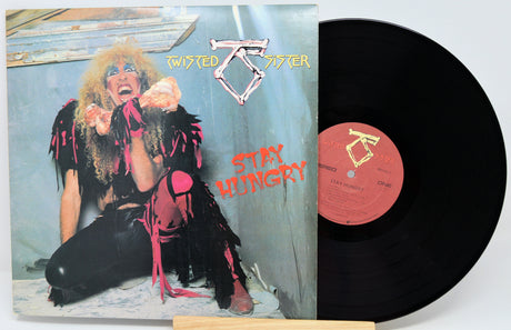 Twisted Sister 'Stay Hungry' vinyl record album with the printed cover in front and the black LP record partially pulled out, showing the orange center label.