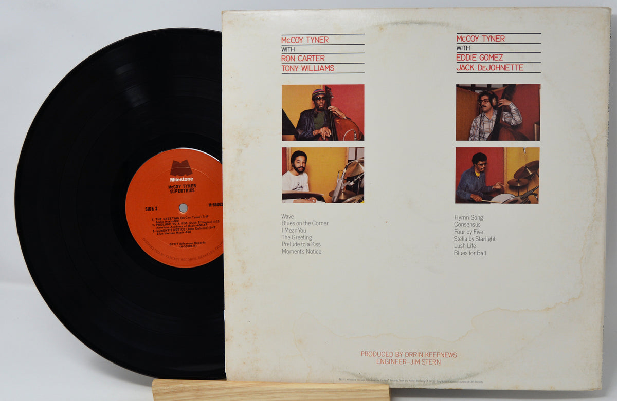 A vinyl record partially pulled from its sleeve, showing the black record with an orange label and the cream-colored printed album cover behind it.