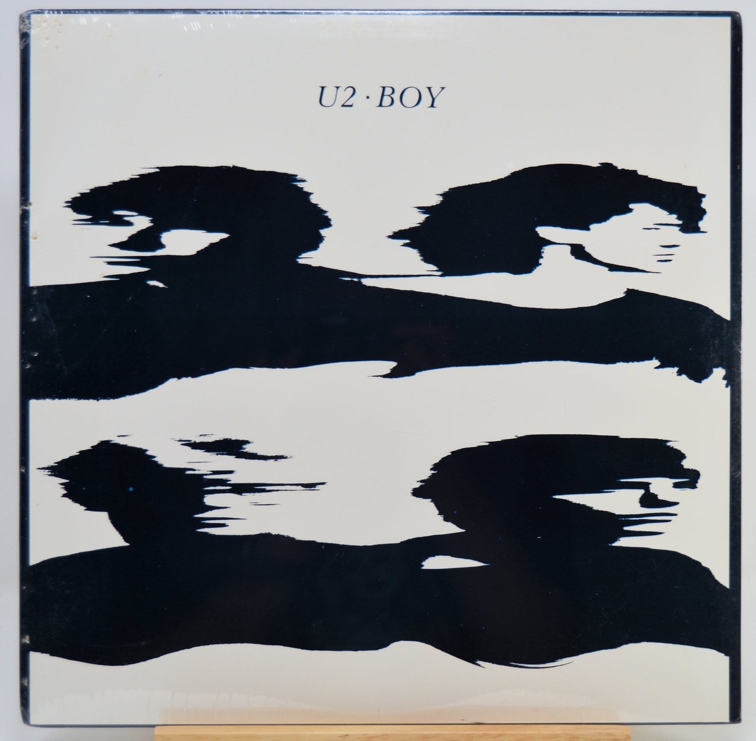 U2 Boy album cover featuring a minimalist black abstract brushstroke design on a white background with the text 'U2 BOY' at the top.