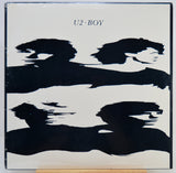 U2 Boy album cover featuring a minimalist black abstract brushstroke design on a white background with the text 'U2 BOY' at the top.