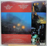Back cover of a vinyl record sleeve for Gloria's '11 o'clock tick tock' / 'I will follow' party girl, featuring red text bands, a large blue-toned beach scene with glowing lights, and a vertical collage of photos on the right side.