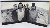 Album cover with four band members in a desert landscape