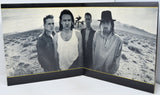 Album cover with a black and white photo of four people in a desert landscape.