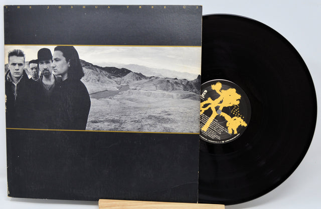 Vinyl record with a black and white cover featuring a group of people and a desert landscape.