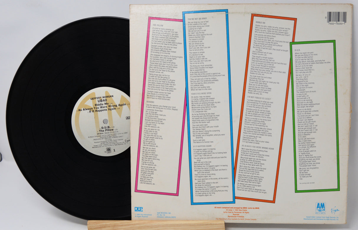Vinyl record with a white label and a cover featuring text and colorful borders.
