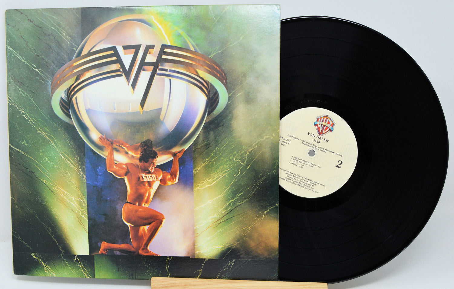 Vinyl record with a colorful cover featuring a person holding a sphere, on a white background.