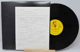 Vinyl record with a yellow label and black cover on a white background