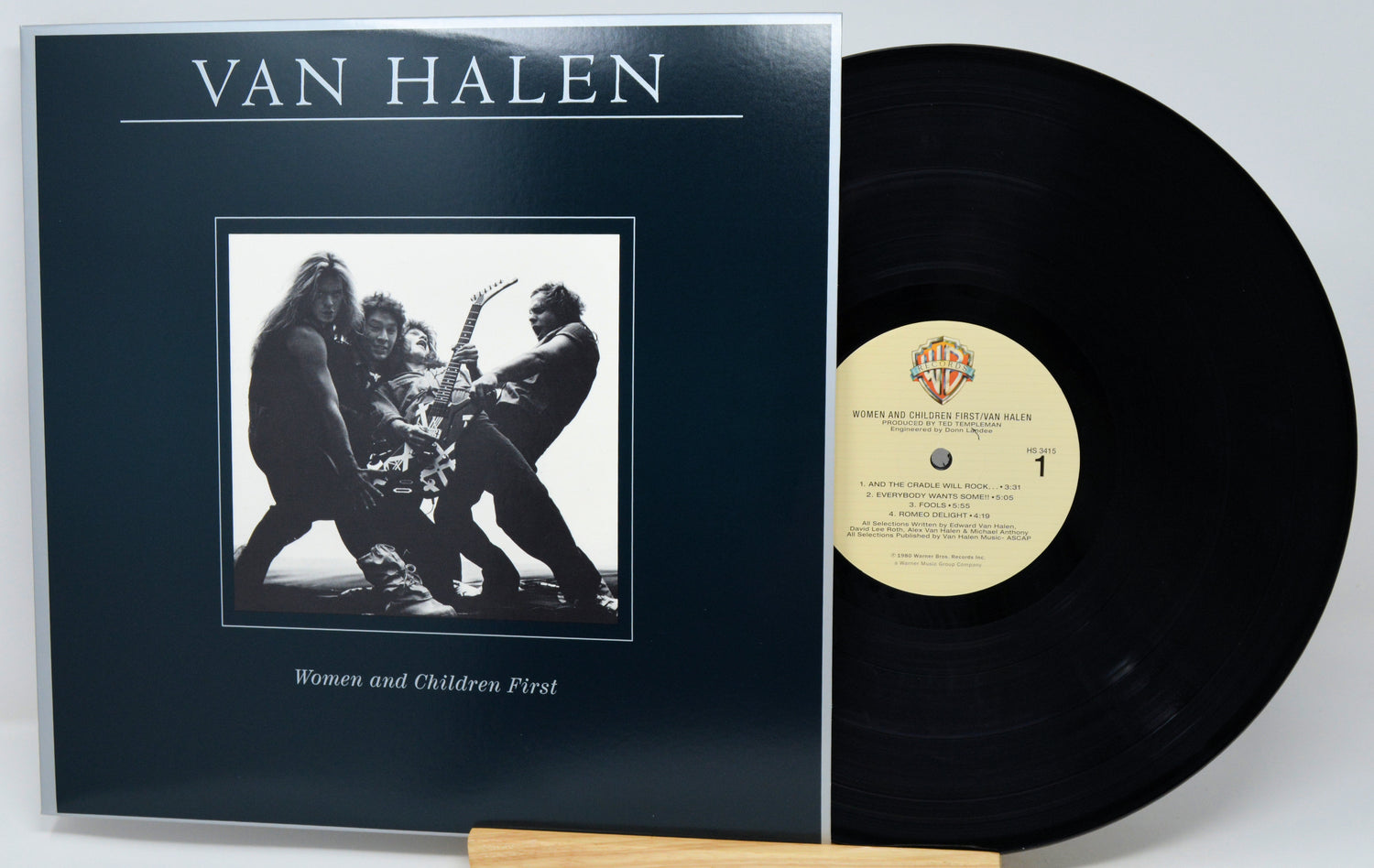 Van Halen 'Women and Children First' vinyl record with the black LP partially pulled from the sleeve, photographed on a light gray background.