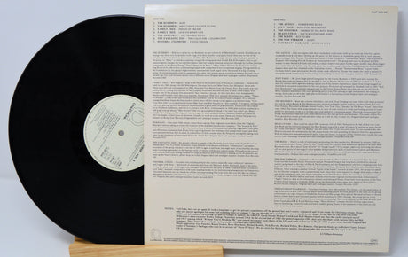 Vinyl record sticking out of the sleeve and showing the back cover which is black text on a white background.