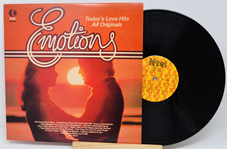 Vinyl record with orange cover featuring a couple and sunset, labeled 'Emotions'.