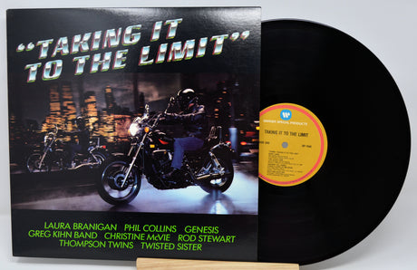Vinyl record album 'Taking It to the Limit' with the black LP partially pulled from the cover, showing a motorcycle rider at night and a yellow label on a white background.