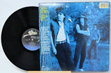 Vinyl record with a blue and white cover featuring three people in a park.