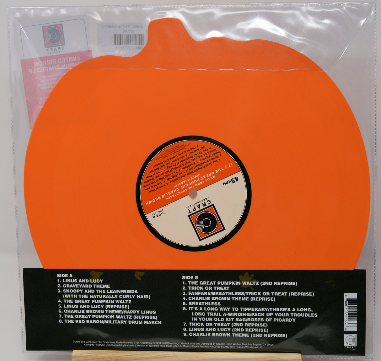Orange vinyl record sleeve for the band Calypso's album 'Lurkin and Lucy', showing the back of the package with track listings and a small wooden display stand.