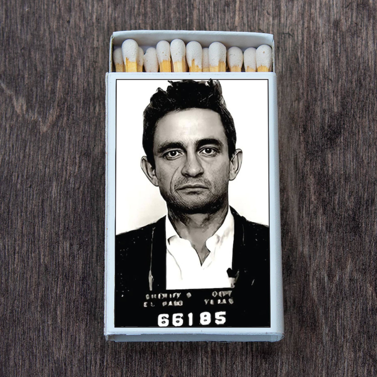 Decorative matchbox featuring a vintage mugshot portrait on the cover against a wooden background