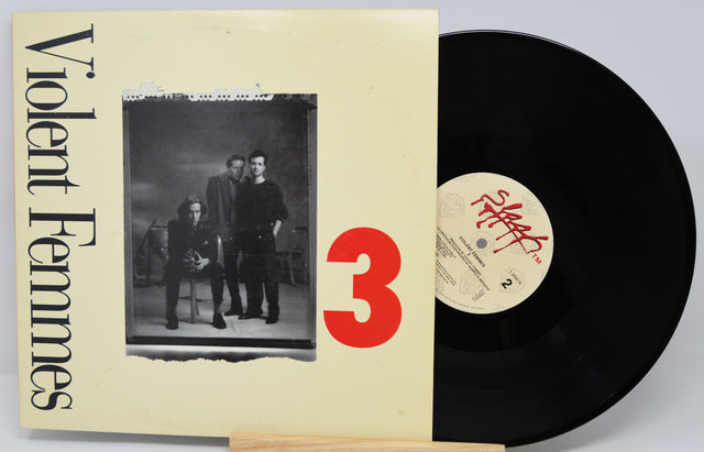 Vinyl record with 'Violent Femmes' album cover showing three people and a red number 3.