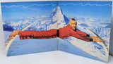 Person lying on skis with a mountainous landscape in the background