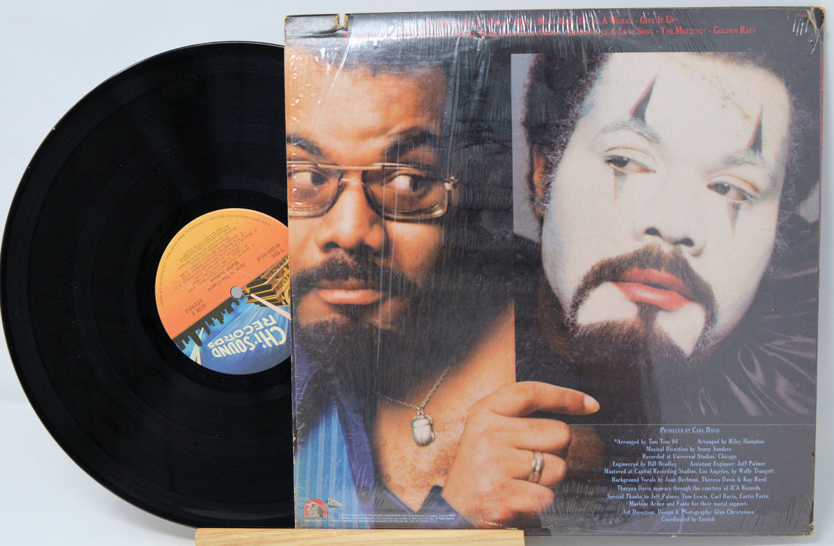 Vinyl record with a cover featuring two faces and a label on a light blue background