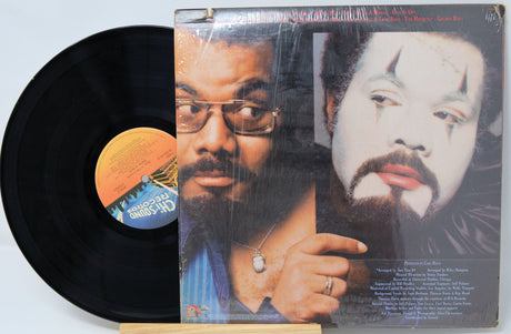 Vinyl record with a cover featuring two faces and a label on a light blue background