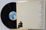 Vinyl record with cover featuring a person sitting and track listings.