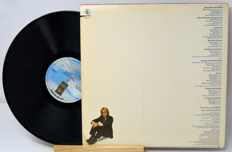 Vinyl record with cover featuring a person sitting and album details.
