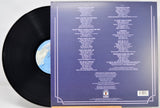 A vinyl record partially pulled from its sleeve, showing the back of the packaging with printed track listings and a blue label visible on the black record.