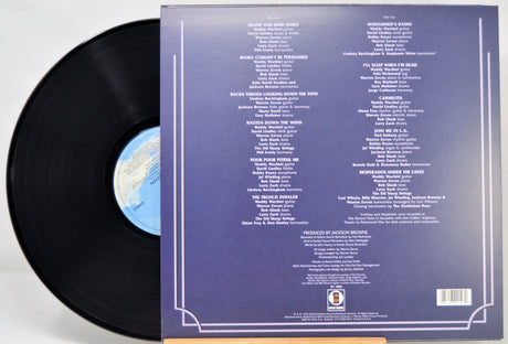 A vinyl record partially pulled from its sleeve, showing the back of the packaging with printed track listings and a blue label visible on the black record.