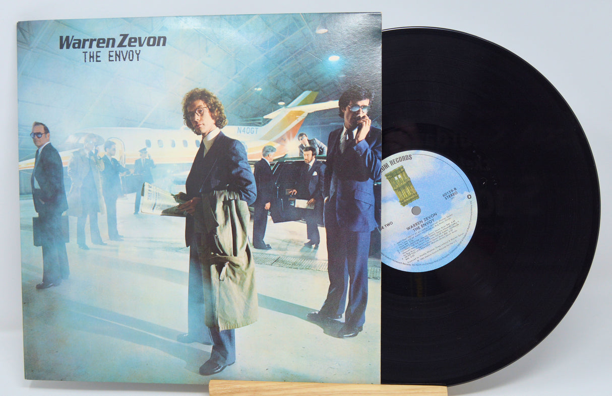 A used vinyl record of Warren Zevon's album 'The Envoy' with the cover image featuring the artist next to an airplane.