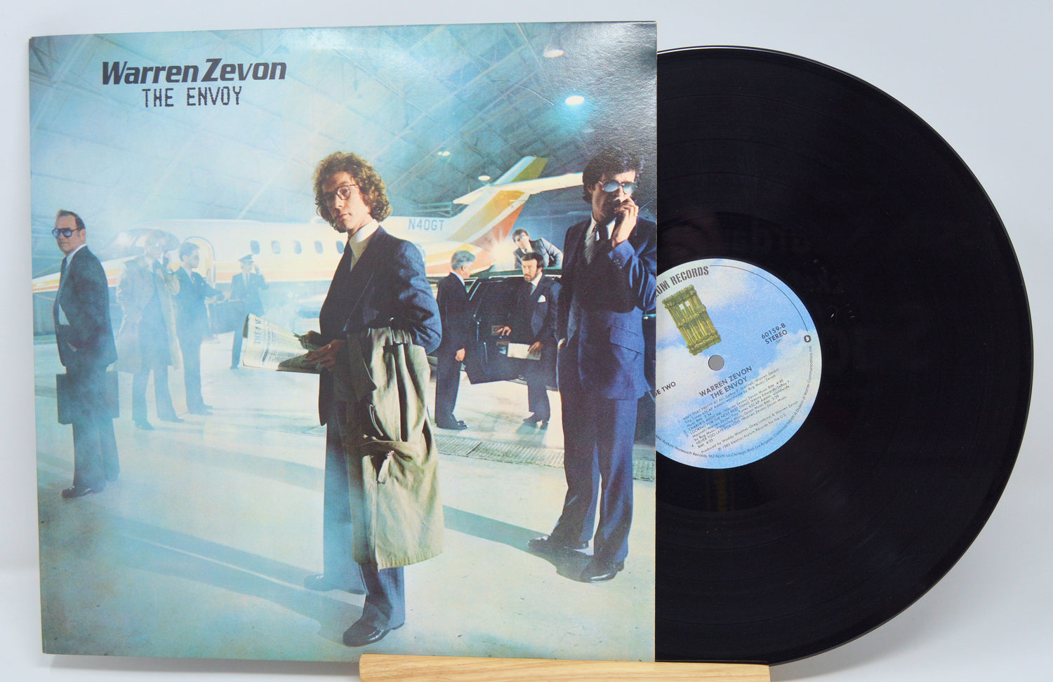 A used vinyl record of Warren Zevon's album 'The Envoy' with the cover image featuring the artist next to an airplane.