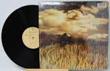 Vinyl record with a landscape cover featuring a field and clouds.