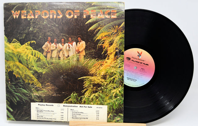 Vinyl record with cover featuring a group of people in a jungle setting titled 'Weapons of Peace'.