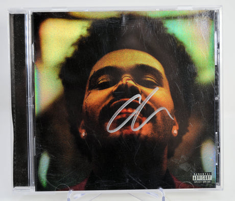 The Weeknd CD cover with a stylized portrait and signature on a white background. Autographed