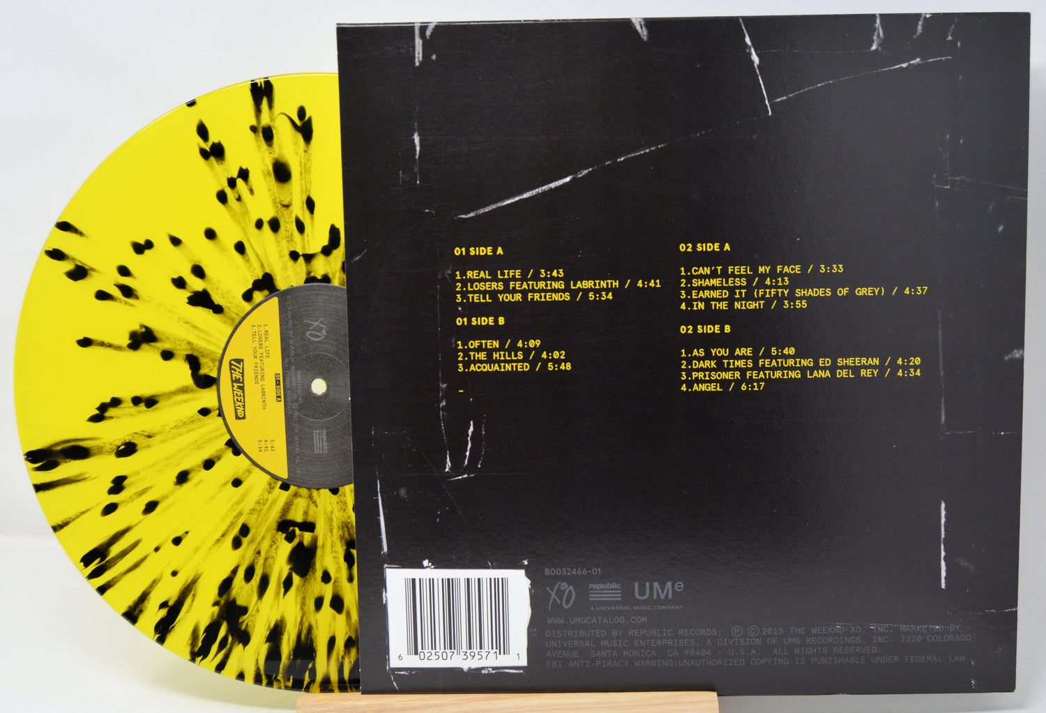 Vinyl record with yellow and black pattern on one side and back cover with text on the other, on a white background.
