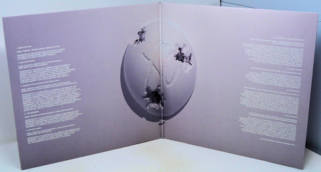 Open book with purple cover featuring a central circular design and text on either side.